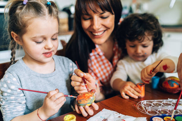 istock Mother painting Easter eggs with her children 1129198405