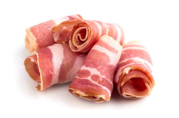 Slices of bacon on a white background. Raw rolled bacon on a white background. Slices of bacon on a white background. Raw rolled bacon on a white background. twisted bacon stock pictures, royalty-free photos & images
