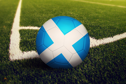 Scotland ball on corner kick position, soccer field background. National football theme on green grass.