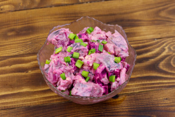 Tasty salad with herring, beetroot, eggs, onion and mayonnaise on wooden table