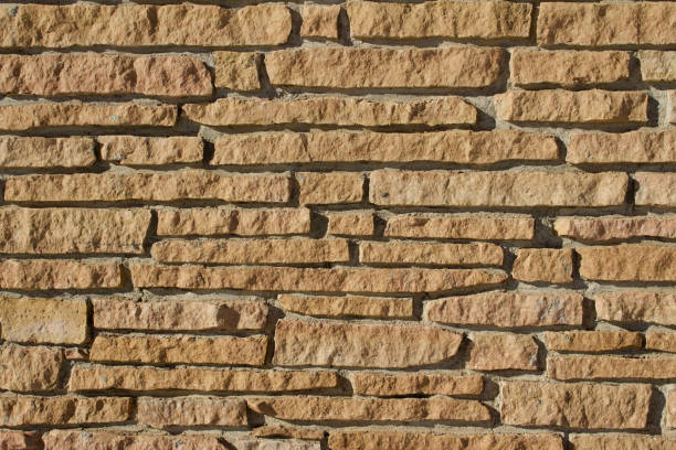 istock Rugged tan color stone wall background of rough stone bricks 1129203066
