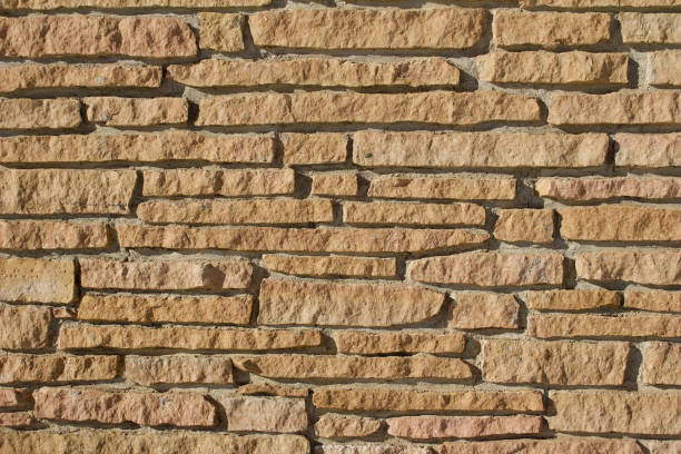istock Rugged tan color stone wall background of rough stone bricks 1129203089