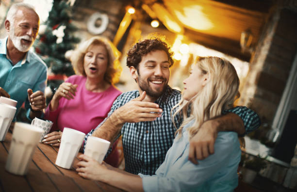 Weekend with in laws. Closeup of a mid 20's couple spending a weekend at his parent's house. They are having some drinks on a porch, talking and laughing. father in law stock pictures, royalty-free photos & images