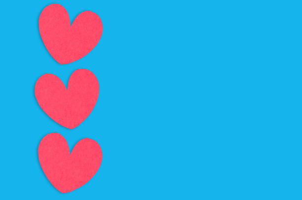 istock Three red paper hearts on blue table. Top view. Valentines Day concept. Copy space for your text 1129203921