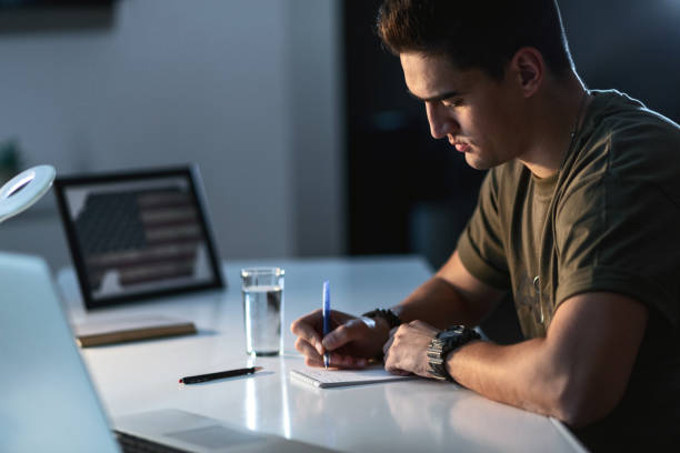 istock Young US army soldier writing letter at the desk. 1129204831