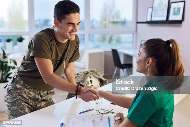 Happy Military Man Shaking Hands With Female Doctor At Clinic Stock Photo - Download Image Now
