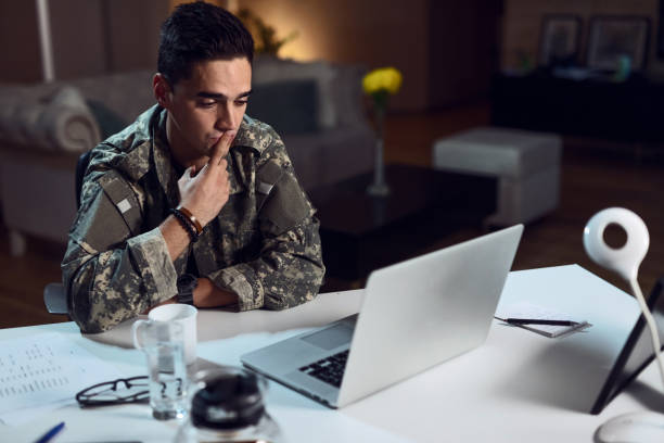 istock Young military man sending a kiss while having video call on laptop. 1129205605