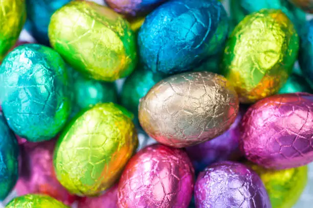 heap of gold, blue, yellow, rose foiled chocolate easter eggs , easter background