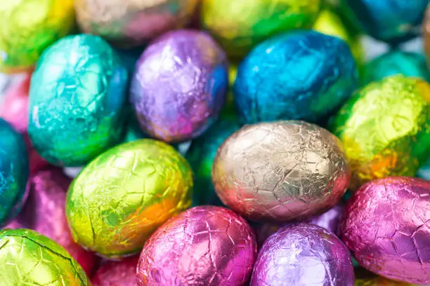 heap of gold, blue, yellow, rose foiled chocolate easter eggs , easter background
