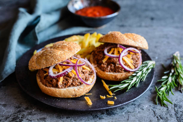 Sloppy Joe sandwich served with French fries Homemade Sloppy Joe sandwich sprinkled with Cheddar cheese and onion, served with French fries sloppy joes stock pictures, royalty-free photos & images