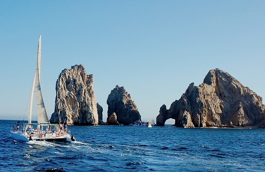 This is el Arco in the San Lucas Bay, Finisterra, or lands end, a tourist mecca at the southern extremity of Baja California Sur with tourist boats taking sightseers for a memorable jaunt.  The tourist on the catamaran are looking at the scenery and deeply involved