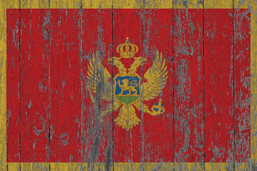 Flag of Montenegro painted on worn out wooden texture background.
