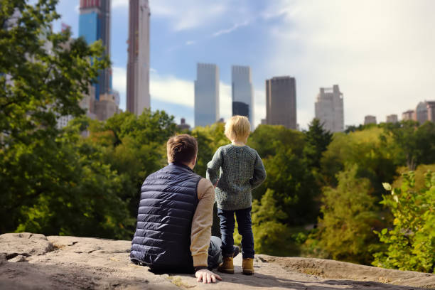 man und ihr charmanter kleiner sohn bewundern die aussicht im central park, new york - skyscraper city life urban scene building exterior stock-fotos und bilder