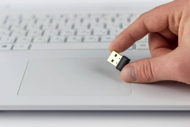 istock mini flash drive in hand on laptop keyboard background 1129228865