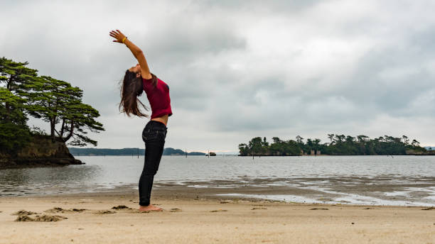 Young woman doing morning yoga on a beach stock photo