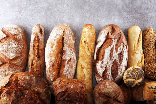 istock Assortment of baked bread and bread rolls on stone table background 1129229473