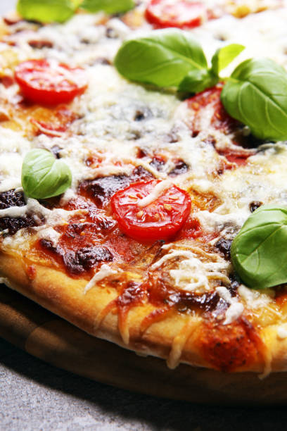 istock Vegetarian Italian pizza with melted cheese, red tomatoes and green basil on a table decorated by cheese, tomato and cherry tomatoes 1129231034
