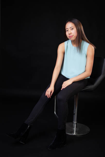 istock Young Asian Female Seated Portrait in Studio on Black Background 1129238918