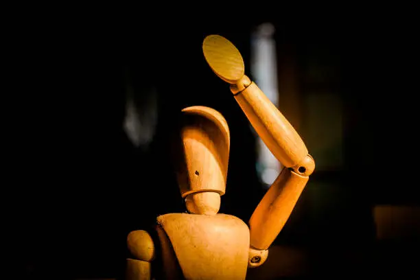 Wooden mannequin, light in the face, contrast, black background