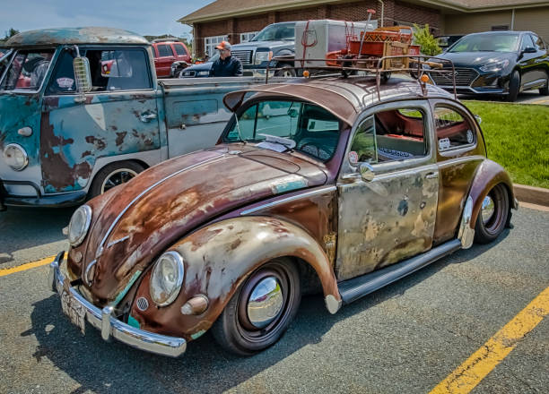 Bangkok, Thailand - February 15, 2014: Thai people are standing between many VW Beetle oldtimers on Siam VW festival of private owners. A group of men is watching a beetle with rusty styled chaissis and open top.