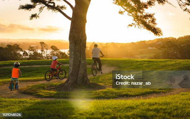 Kids Following Father On Bike Stock Photo - Download Image Now - New Zealand, Family, Auckland