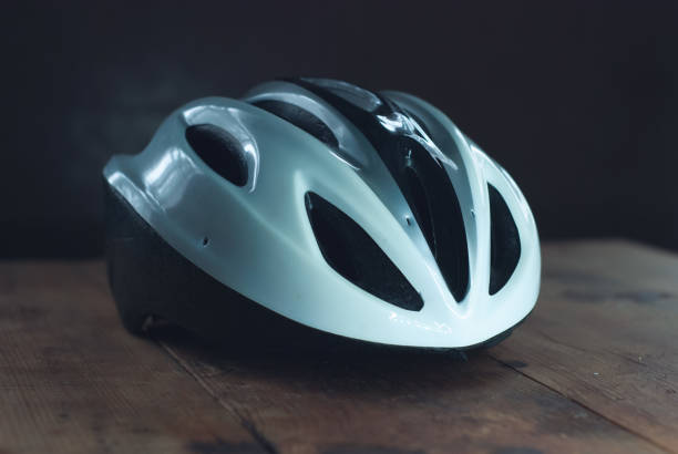 istock Bicycle helmet on wooden table, white plastic helmet on dark background, protection for cyclist, 1129270836