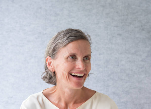 istock Middle aged woman laughing against grey background 1129277000