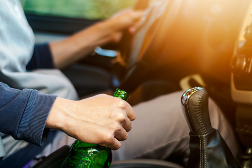 Drinking and driving ,man drinking alcohol and using mobile phone while driving car ,concept drive safely while using a cell phone or drunk alcohol