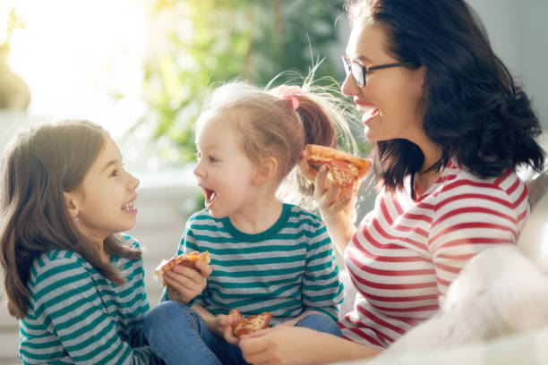 istock Mother and daughters eating pizza 1129283107