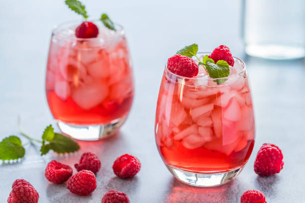 Refreshing red drink with fresh raspberries and crushed ice Two refreshing red translucent drinks with ice and raspberries. The raspberry juice is garnished with a green leaf, and there are pieces of ice and raspberries scattered around the drinks. blended drink photos stock pictures, royalty-free photos & images