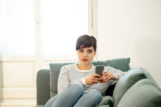 istock Happy attractive short haired young woman on mobile smart phone chatting and using social media apps sitting on couch at home in dating on line,using new technology and social network concept. 1129303215