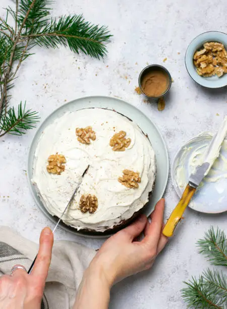 Carrot cake topped with walnuts being sliced