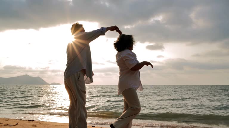 Vacations : Senior couple dancing at beach on sunny day ,Senior couple relaxing by the sea.Senior Holidays.