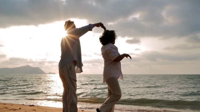 Vacations : Senior couple dancing at beach on sunny day ,Senior couple relaxing by the sea.Senior Holidays.