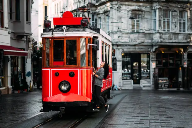 Photo of Girl in a vintage tram on the Taksim Istiklal street in Istanbul. Girl on public transport. Old Turkish tram on Istiklal street, Turkey. Portrait of a smiling young woman posing on a city street