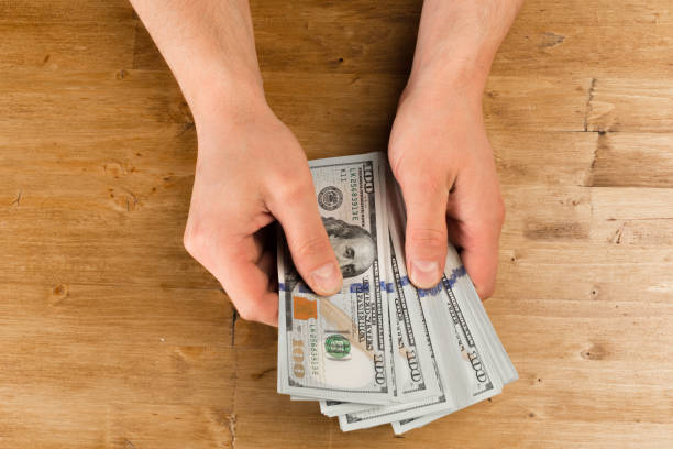 istock Man count the new us dollars on wooden table 1129312102