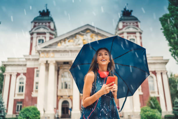 smiling girl with umbrella at a rainy day - rain women umbrella parasol imagens e fotografias de stock