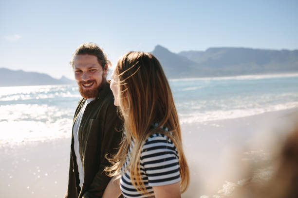 istock Happy couple strolling on the beach 1129317523