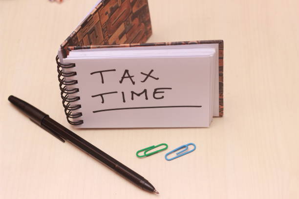 istock top view Illustration for Tax Time, block note at wooden table 1129319594