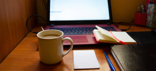 istock home office desk, red laptop, coffee, notebooks, diary, pen 1129320898