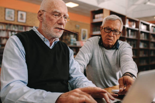 istock Senior men sitting in a classroom working on laptop 1129321036
