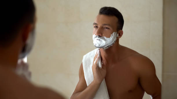 istock Man applying shaving cream to face and beard, ready to change appearance, style 1129322344