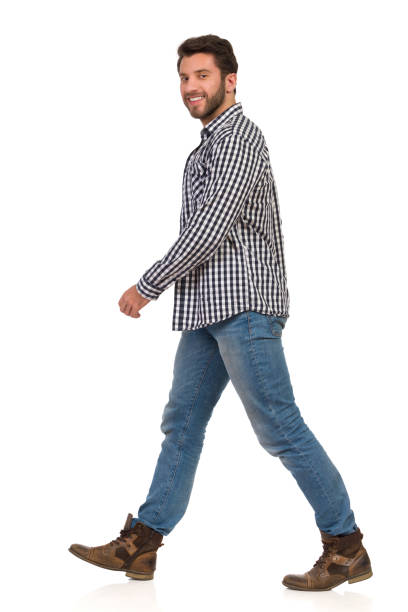 istock Young Man In Jeans, Boots And Lumberjack Shirt Is Walking Side View 1129325647