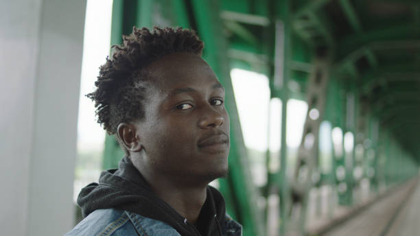 African man posing to a camera. Steel construction of bridge.