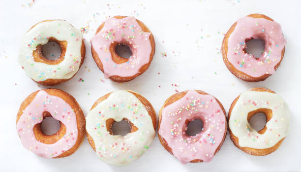 istock Homemade donuts decorated with colored icing and colored sugar on a light background. 1129330788