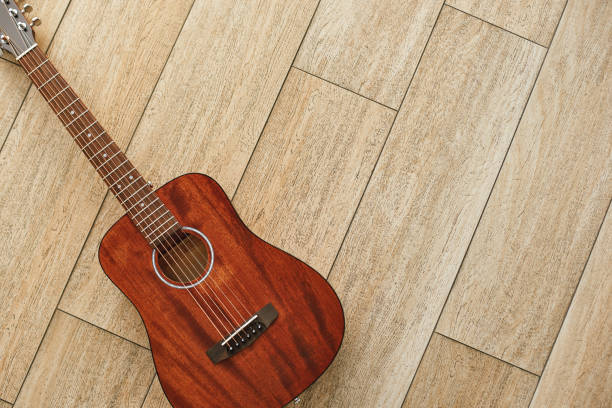 beauté de l'instrument de musique. vue de dessus de la guitare acoustique brune se trouvant sur le plancher en bois. - classical music music musical instrument brown photos et images de collection