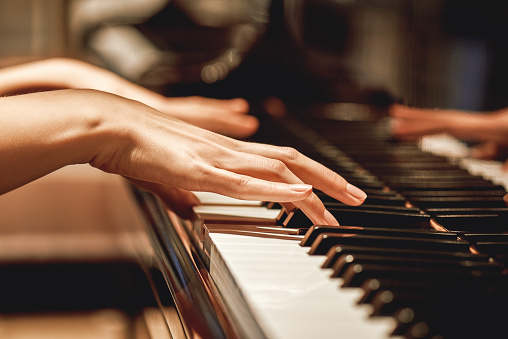 Música clásica favorita... Vista de cerca de manos femeninas suaves tocando una melodía en el piano mientras toma clases de piano photo