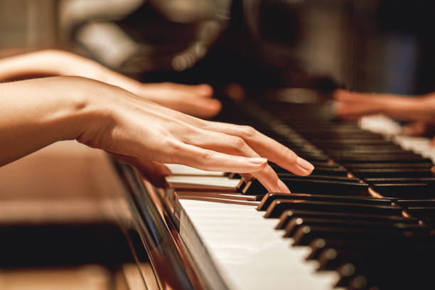 música clássica favorita... feche acima da vista das mãos fêmeas delicadas que jogam uma melodia no piano ao tomar lições do piano - keyboard instrument - fotografias e filmes do acervo