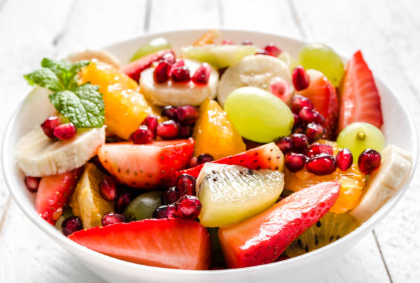 istock Mixed fruit salad on white wooden background 1129332579