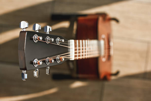 beauté de l'instrument de musique. photo créative de vue de dessus de la guitare acoustique brune avec l'accent sur la tête contre le plancher en bois. - classical music music musical instrument brown photos et images de collection